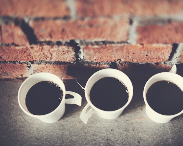 Photo gratuite gros plan de tasses à café avec fond de mur de brique