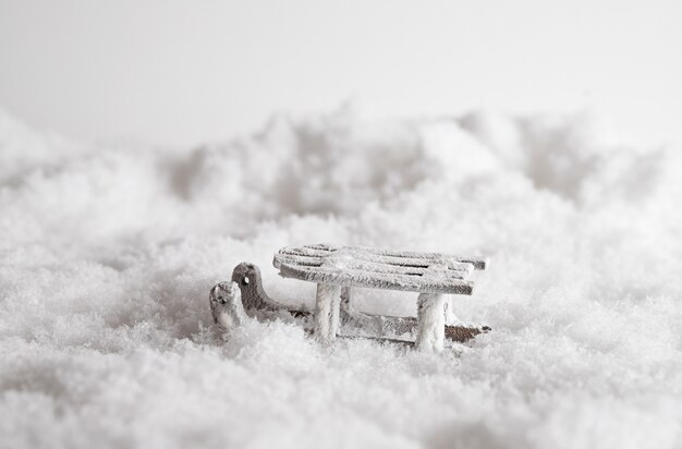 Gros plan d'un traîneau dans la neige, jouet décoratif de Noël dans le fond blanc