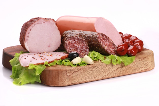 Gros plan sur des tranches de saucisses avec de la laitue verte sur une planche de bois