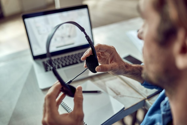 Gros plan sur un travailleur indépendant utilisant des écouteurs au bureau