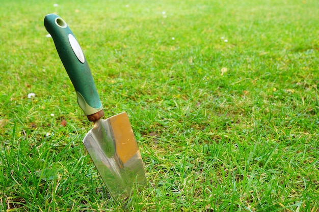 Gros plan d'une truelle à main sur l'herbe verte