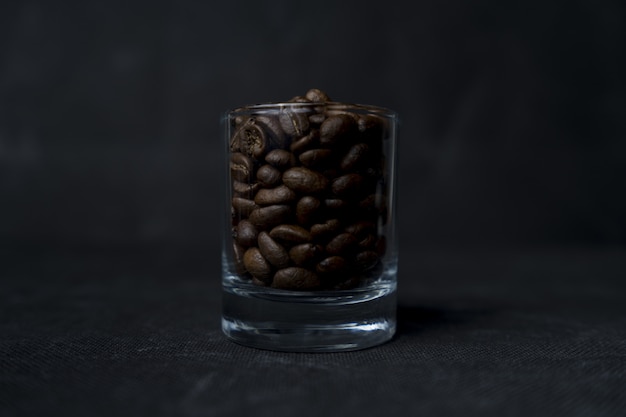 Gros plan d'un verre de grains de café sur une surface sombre