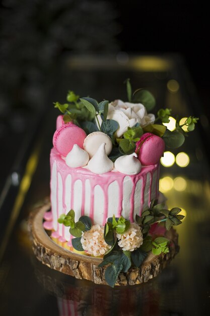 Gros plan vertical d'un beau gâteau avec des fleurs et des macarons