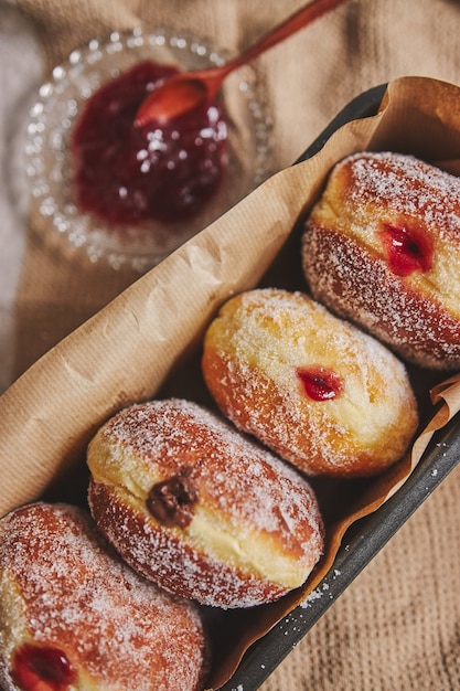 Photo gratuite gros plan vertical de beignets moelleux remplis de confiture dans un récipient sous les lumières