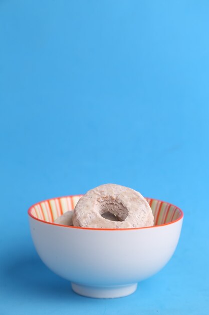 Gros plan vertical d'un bol de biscuits faits maison avec du sucre en poudre sur un fond bleu