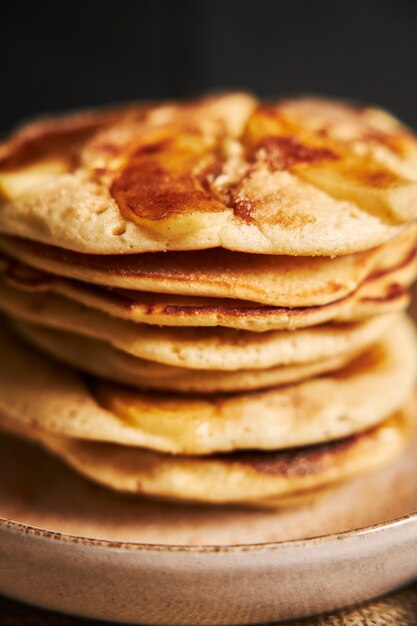 Gros plan vertical de crêpes aux pommes sur une plaque blanche