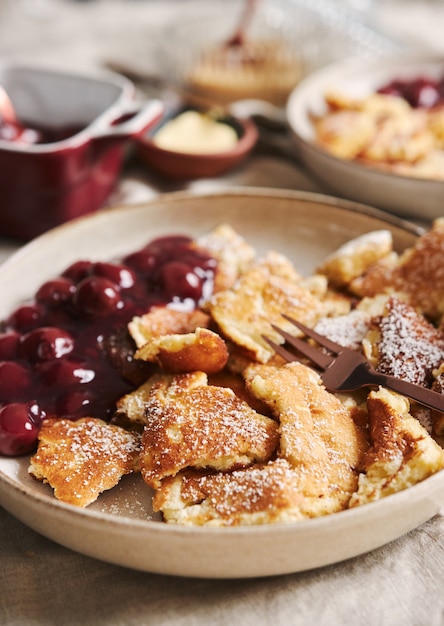 Gros plan vertical de délicieuses crêpes moelleuses avec cerise et sucre en poudre