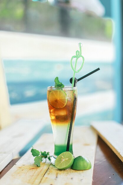 Gros plan vertical d'un délicieux cocktail froid sur la table avec des limes sous les lumières