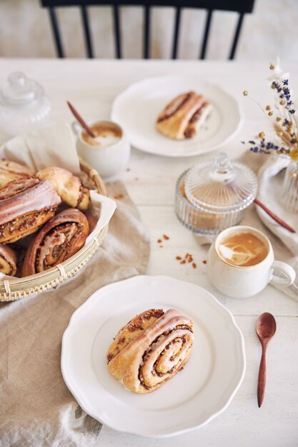 Gros plan vertical de délicieux escargots aux noix avec du café cappuccino sur la table en bois blanc