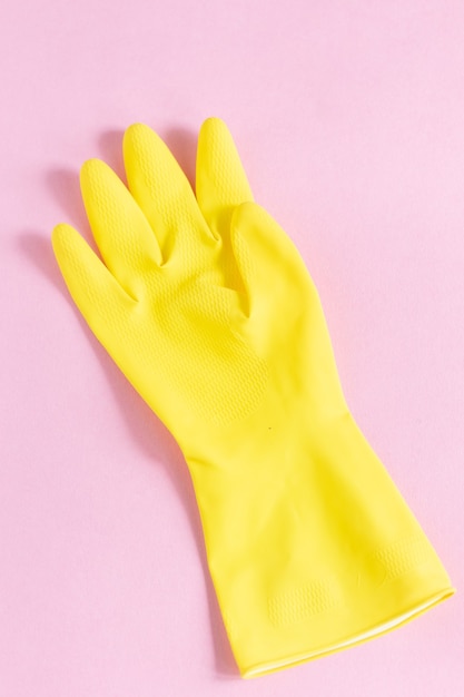 Photo gratuite gros plan vertical d'un gant en plastique jaune sur une surface rose