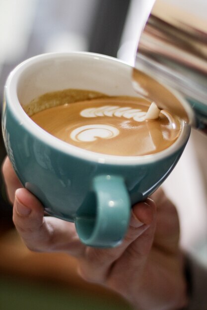 Gros plan vertical sélectif shot de café avec latte art dans une tasse en céramique bleue sur une surface en bois