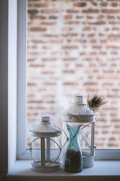 Photo gratuite gros plan vertical sélectif tourné de grandes et moyennes lampes lanterne en verre sur un rebord de fenêtre