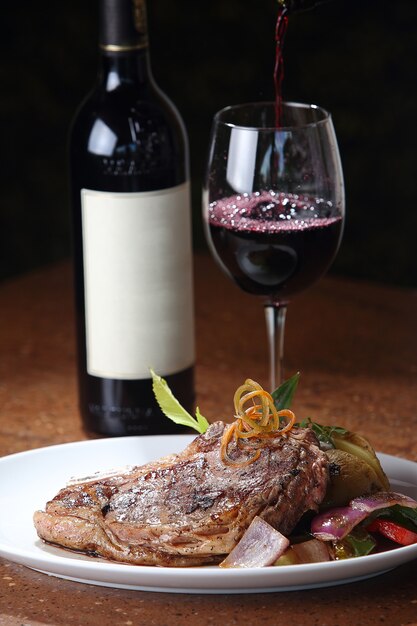 Gros plan vertical d'un steak en T fraîchement grillé et un verre de vin en arrière-plan