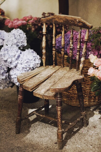 Gros plan vertical tiré d'une chaise en bois vintage entourée de paniers avec des fleurs