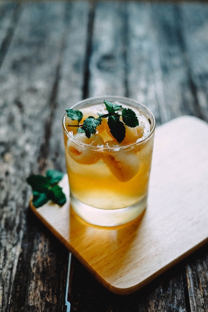 Photo gratuite gros plan vertical tourné d'un cocktail alcoolisé dans un verre sur des montagnes russes en bois avec une feuille de menthe sur le dessus