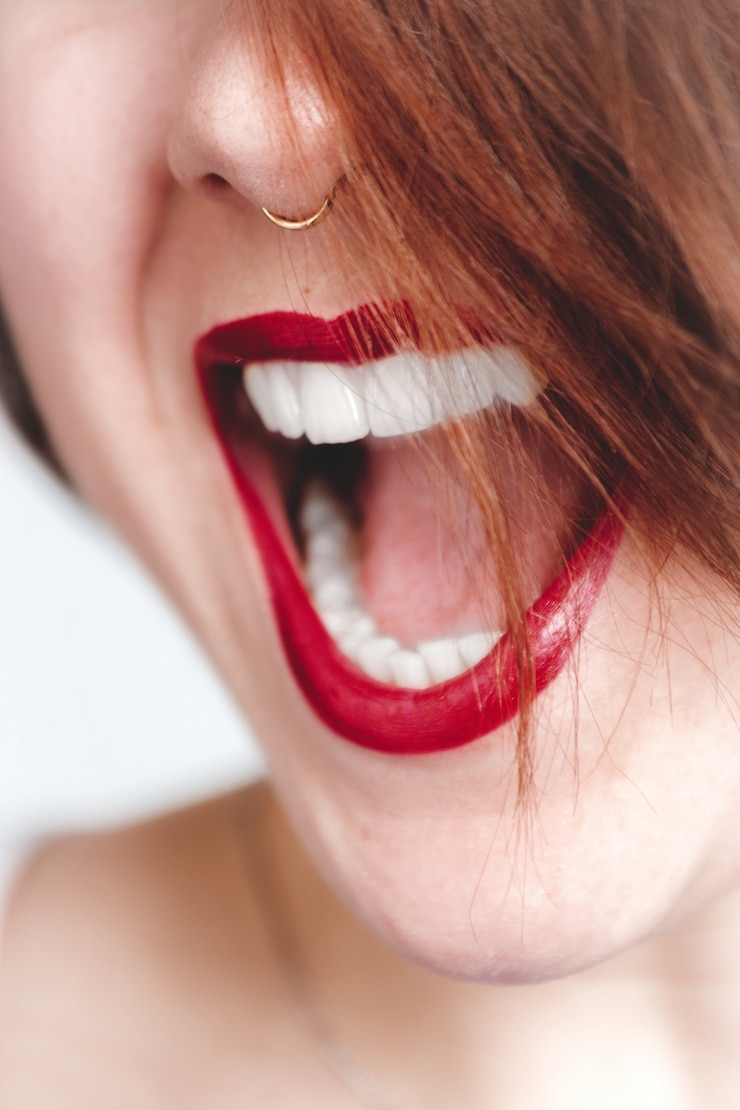 Photo gratuit gros plan vertical tourné d'une femme avec du rouge à lèvres ouvrant la bouche