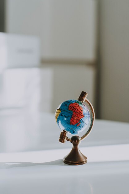 Gros plan vertical tourné d'un petit globe décoratif sur un bureau blanc et floue