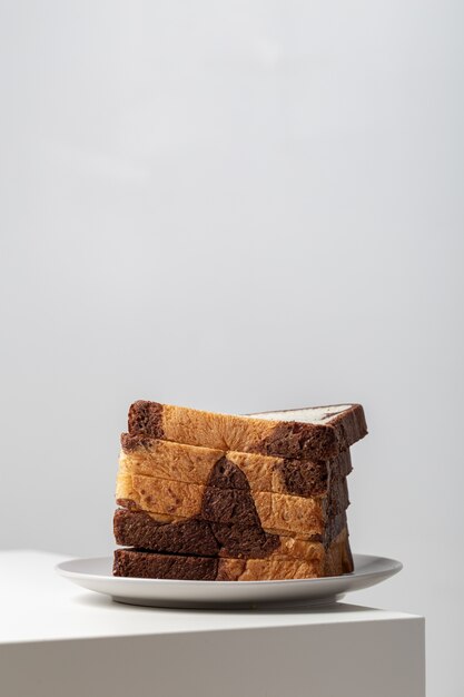 Gros plan vertical de tranches de pain blanc mélangé avec du chocolat sur une assiette sur la table sous les lumières