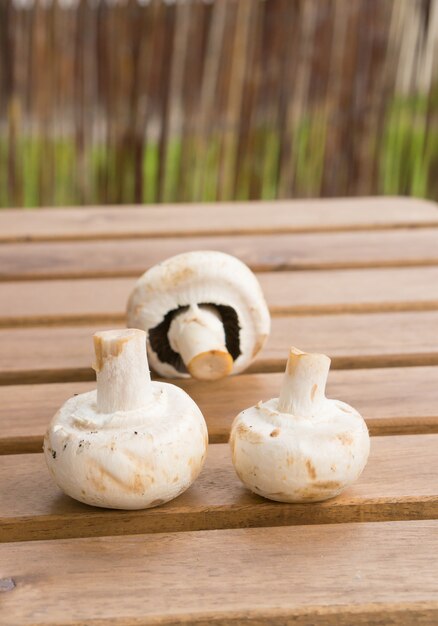 Gros plan vertical de trois champignons frais sur une surface en bois