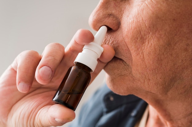 Gros plan vieil homme à l'aide de spray nasal