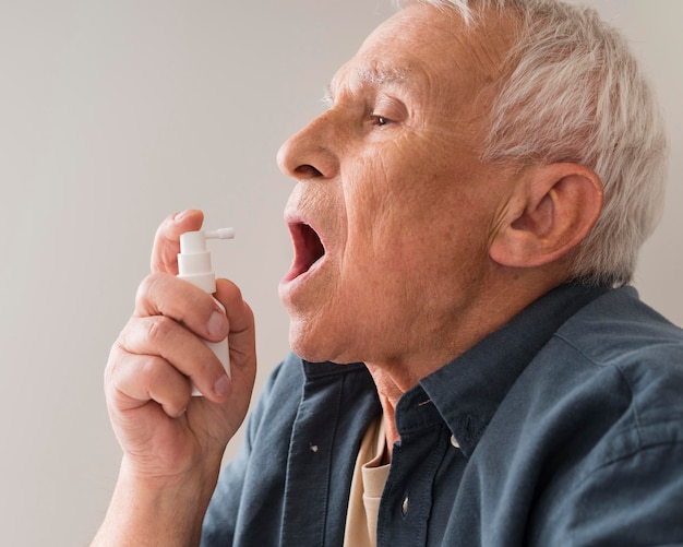 Gros plan vieil homme à l'aide de spray oral