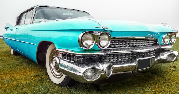 Gros plan d'une voiture turquoise vintage garée sur un champ vert