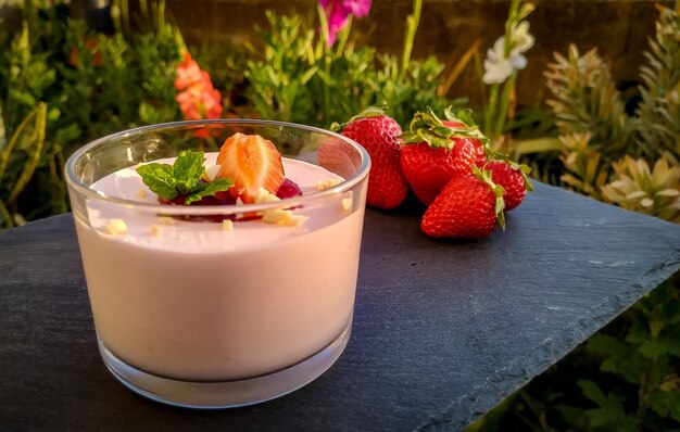 Gros plan de yaourt aux fraises avec des fraises sur le tableau noir