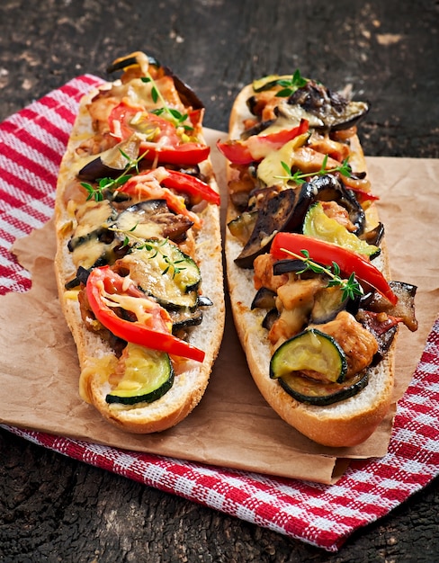 Gros sandwich aux légumes grillés (courgettes, aubergines, tomates) au fromage et au thym sur fond de bois ancien