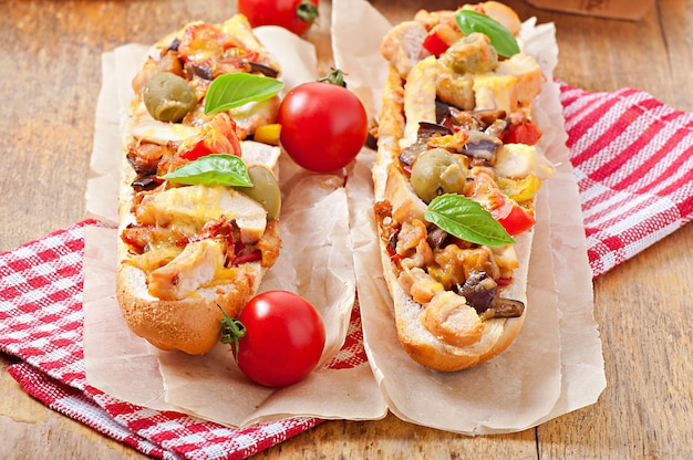 Gros sandwich aux légumes grillés et poulet au fromage et basilic sur une vieille surface en bois