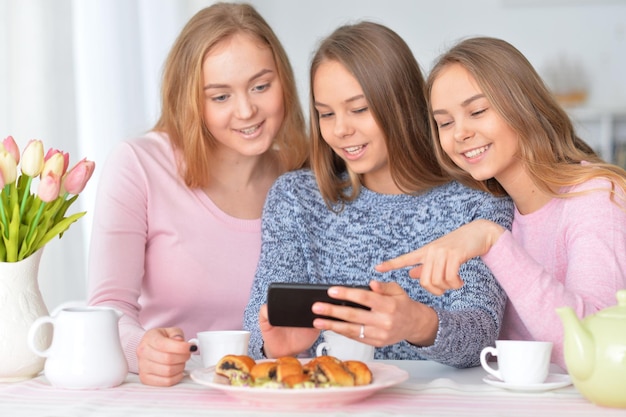 Groupe d'adolescentes assis à table avec smartphone