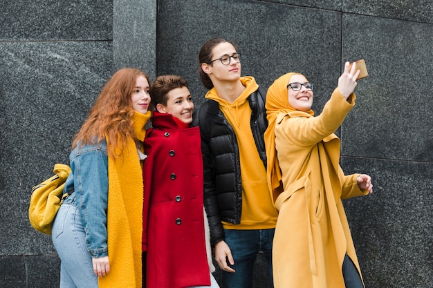 Groupe d'adolescents heureux prenant un selfie ensemble