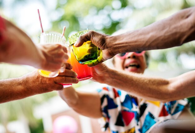 Groupe d&#39;adultes âgés divers appréciant une boisson au bord de la piscine ensemble