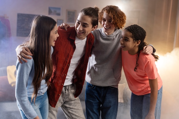 Groupe d'amis adolescents posant ensemble à la maison pendant la fête