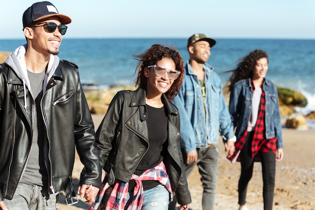 Groupe d'amis africains heureux marchant en plein air sur la plage.