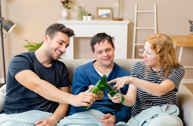 Groupe d'amis applaudir avec de la bière à la maison