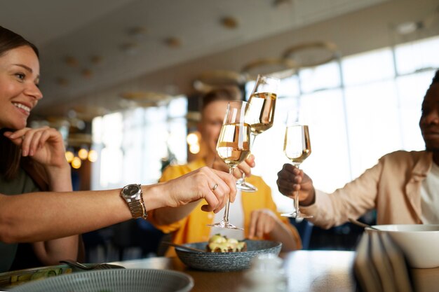 Un groupe d'amis applaudissant avec des verres de vin dans un restaurant