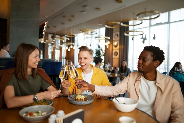 Un groupe d'amis applaudissant avec des verres de vin dans un restaurant