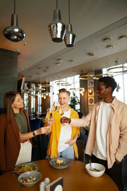 Un groupe d'amis applaudissant avec des verres de vin dans un restaurant