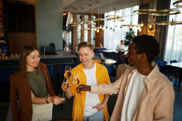 Un groupe d'amis applaudissant avec des verres de vin dans un restaurant