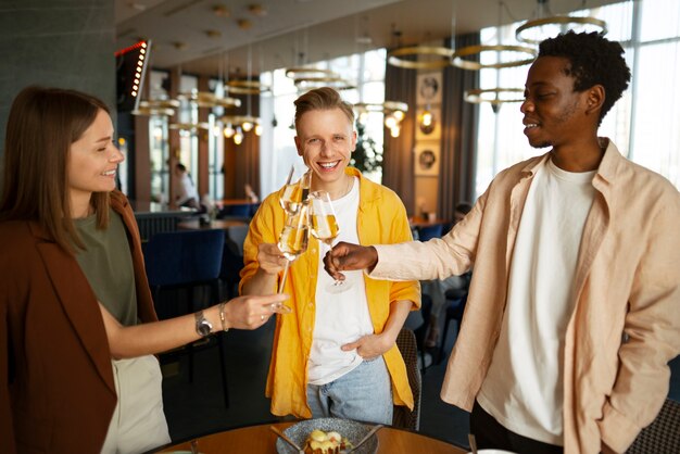 Un groupe d'amis applaudissant avec des verres de vin dans un restaurant