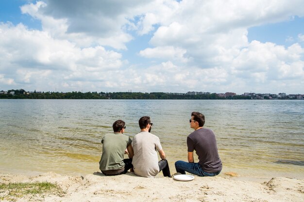 Groupe d&#39;amis assis sur une plage de sable fin