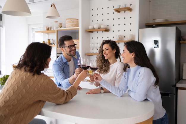 Groupe d'amis buvant du vin dans la cuisine