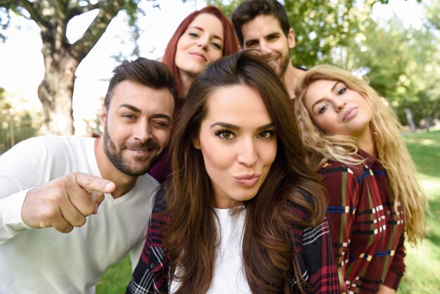 Groupe d&#39;amis dans un selfie avec une fille dans le milieu mettant face baiser