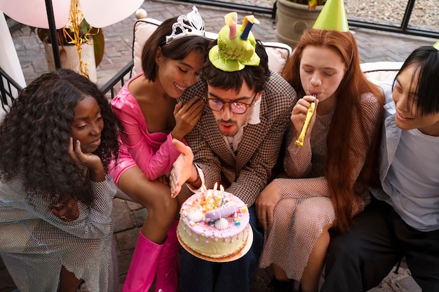 Groupe d'amis avec un gâteau lors d'une fête d'anniversaire surprise