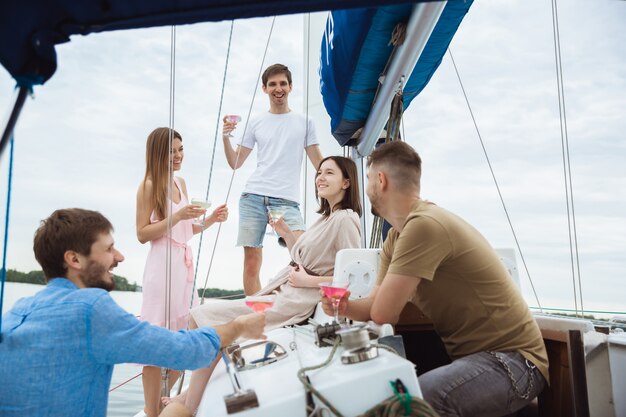 Groupe d'amis heureux de boire des cocktails à la vodka dans un bateau