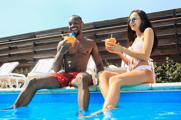 Groupe d'amis jouant et se détendre dans une piscine pendant les vacances d'été