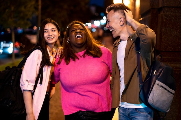 Photo gratuite groupe d'amis la nuit dans les lumières de la ville