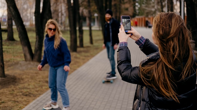 Photo gratuite groupe d'amis de la planche à roulettes dans le parc pendant que la femme prend des photos