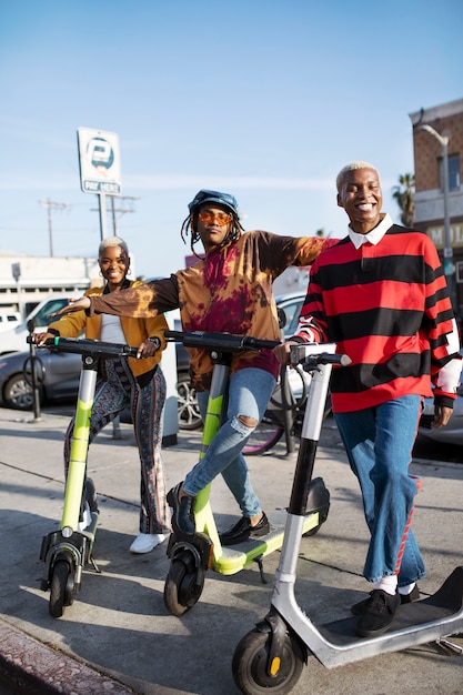 Photo gratuite groupe d'amis posant sur des scooters électriques à l'extérieur de la ville