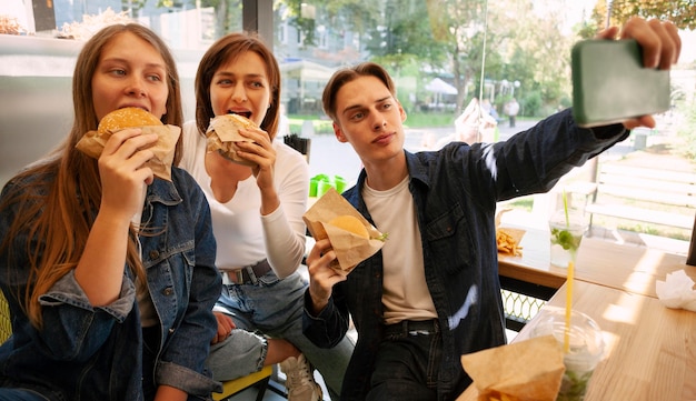 Groupe d'amis prenant selfie en mangeant de la restauration rapide
